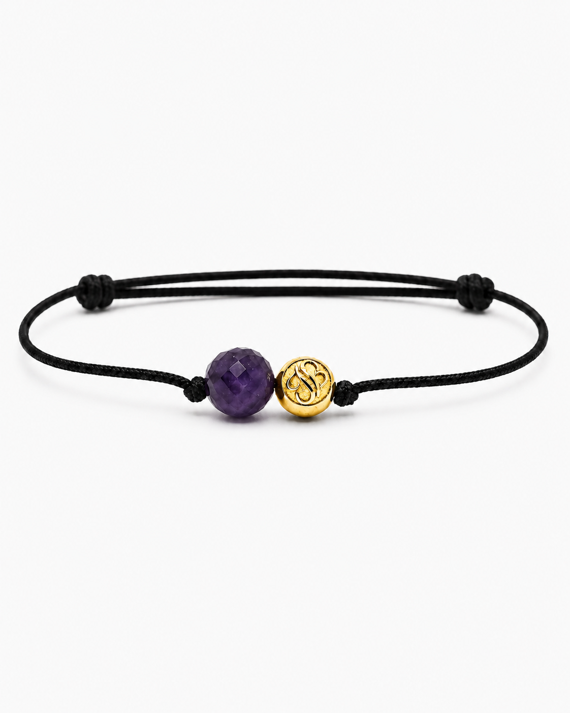 Black cord bracelet with a purple gemstone and gold charm on a white background