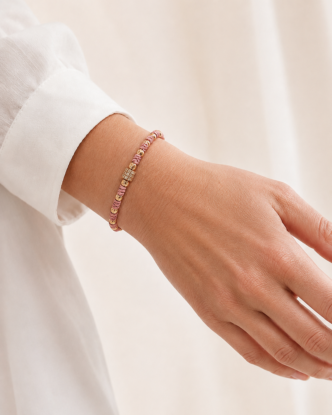 Hand wearing a bracelet on a light background