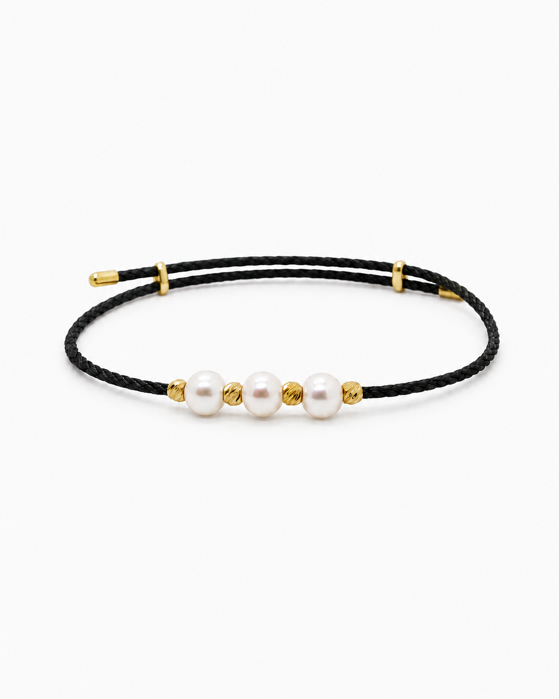 Black cord bracelet with gold accents and three pearls on a white background